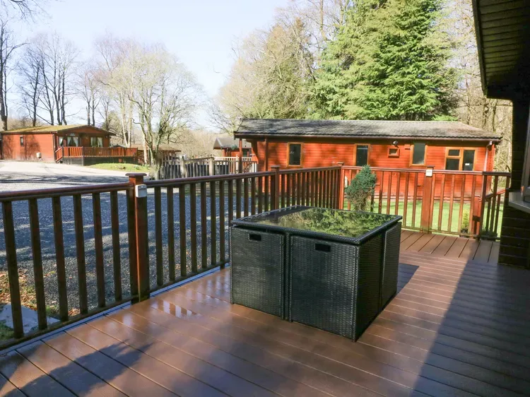 A wooden deck overlooks red cabins, with a rectangular planter near the railing.
