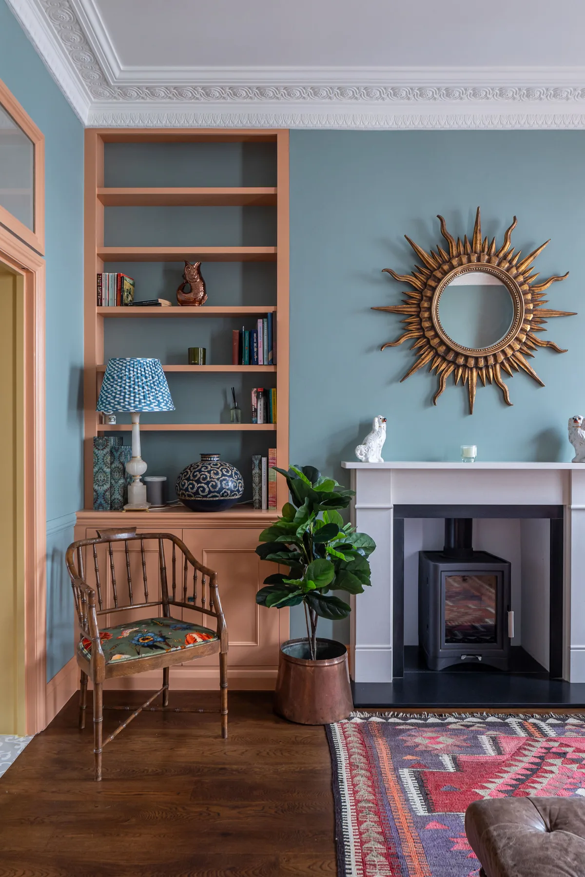 A living room with a fireplace, a patterned rug, and a chair beside a bookcase.