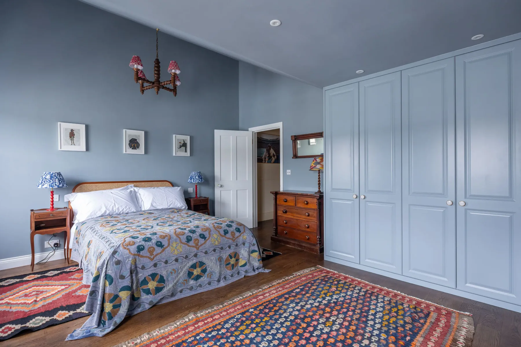 A bedroom with a bed, patterned rugs, and built-in wardrobes.