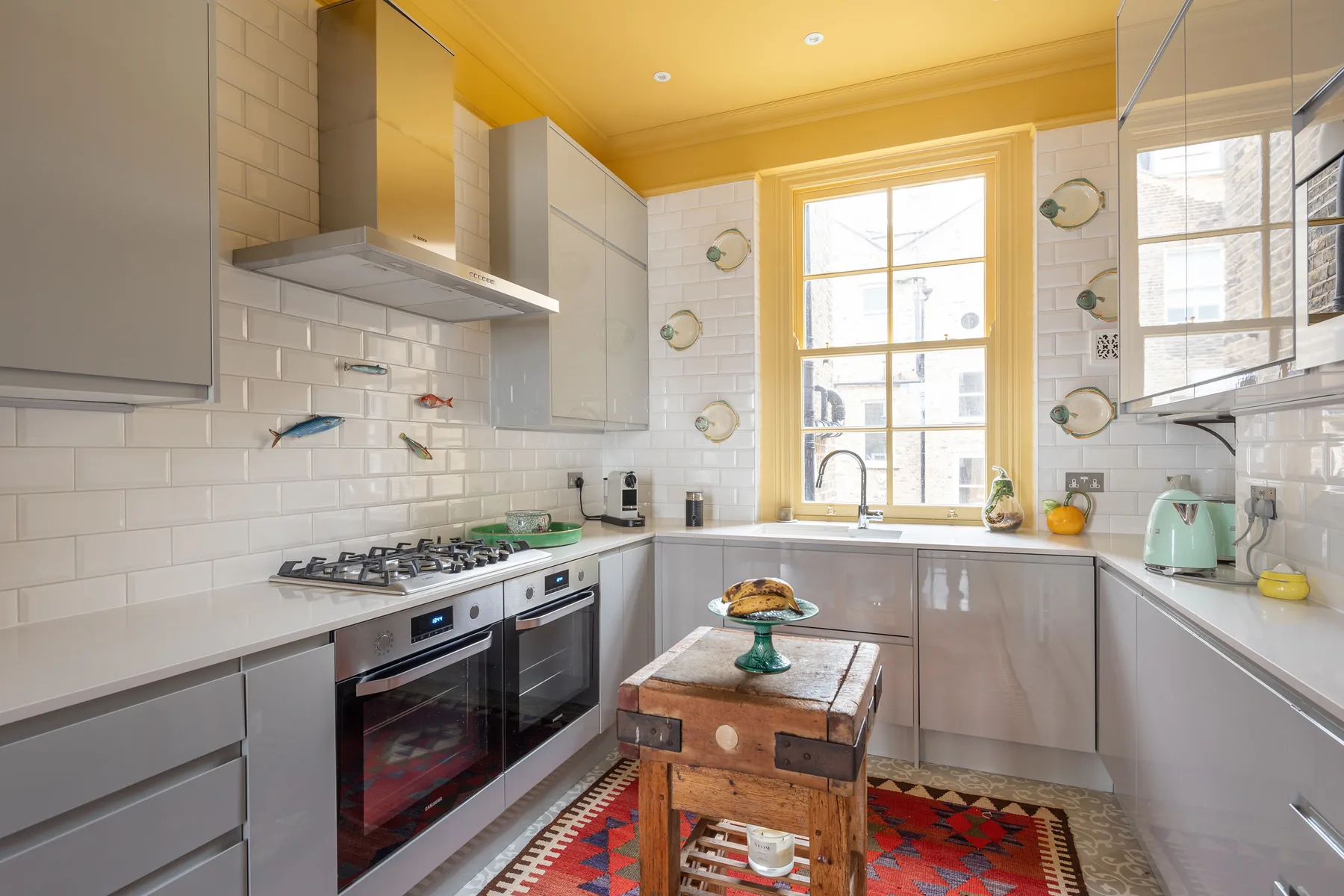 A bright kitchen with white cabinets, a stove, and a central worktable.