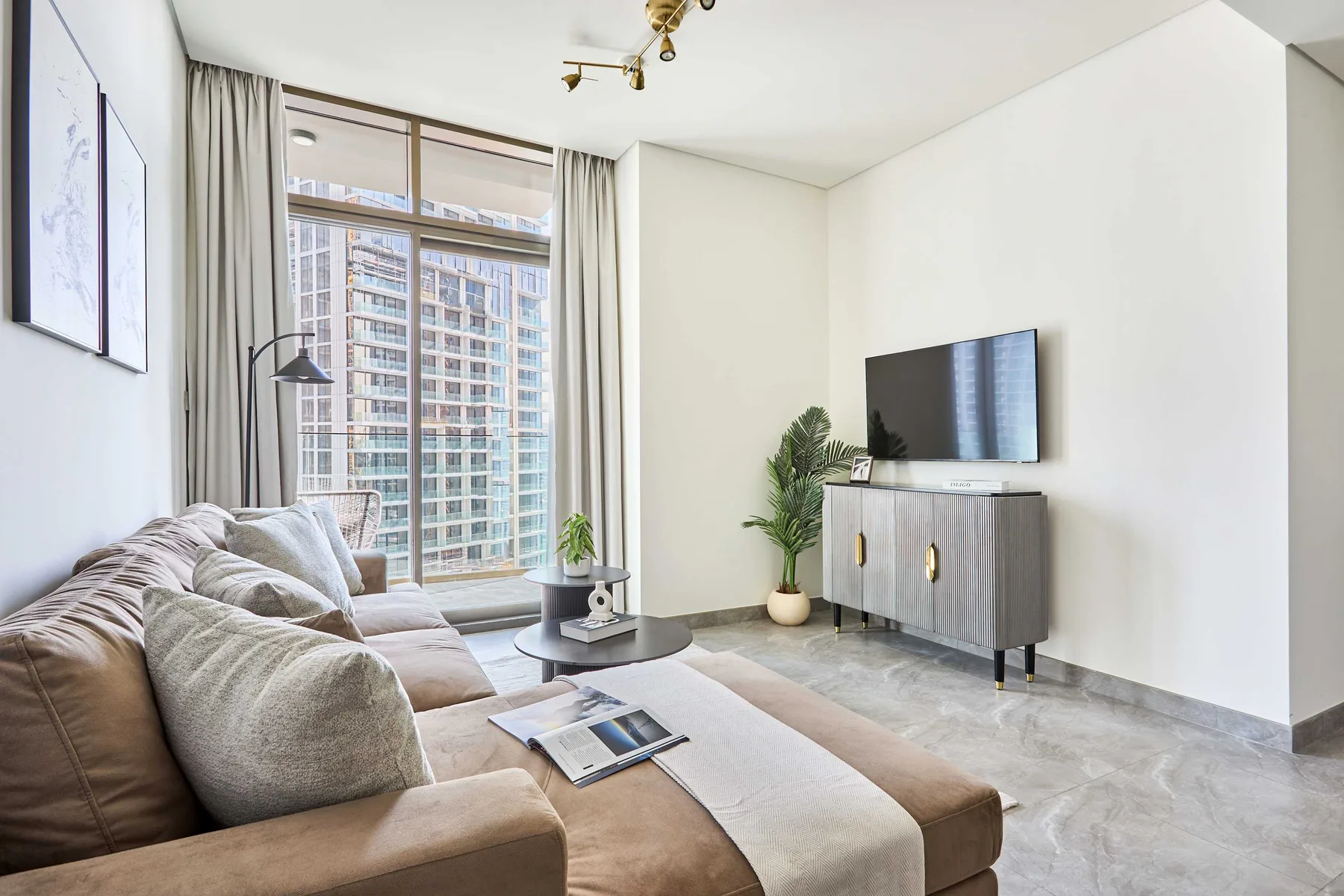 Una sala luminosa con asientos, un televisor y ventanas amplias.