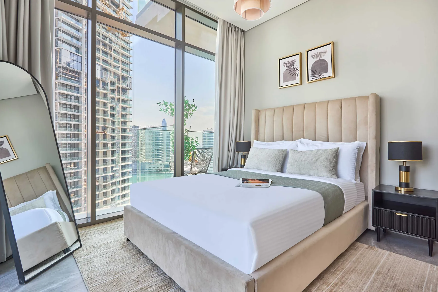 A bedroom with a neatly made bed beside floor-to-ceiling windows.