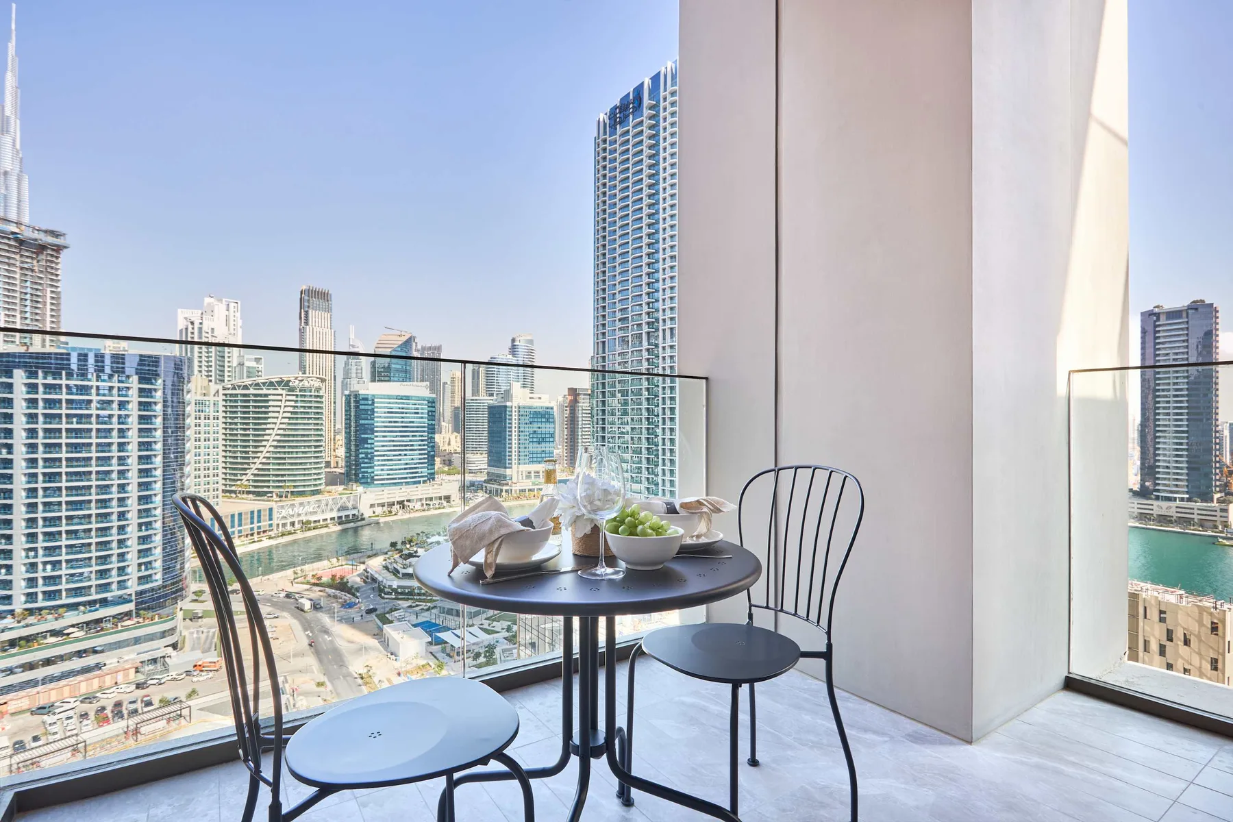 A small balcony seating area overlooks a cluster of city buildings.