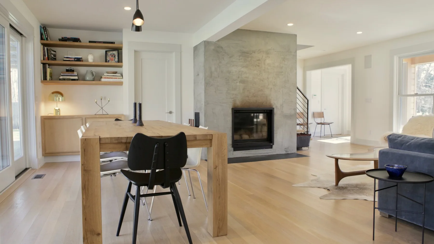 An open-plan living and dining area with a dining table beside a stone fireplace.