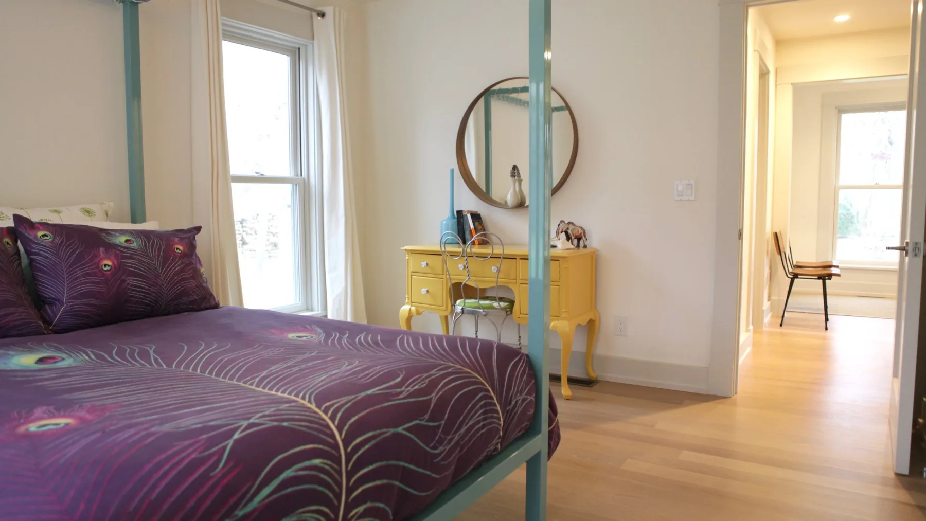 A bedroom with a bed, a yellow vanity, and an open doorway.