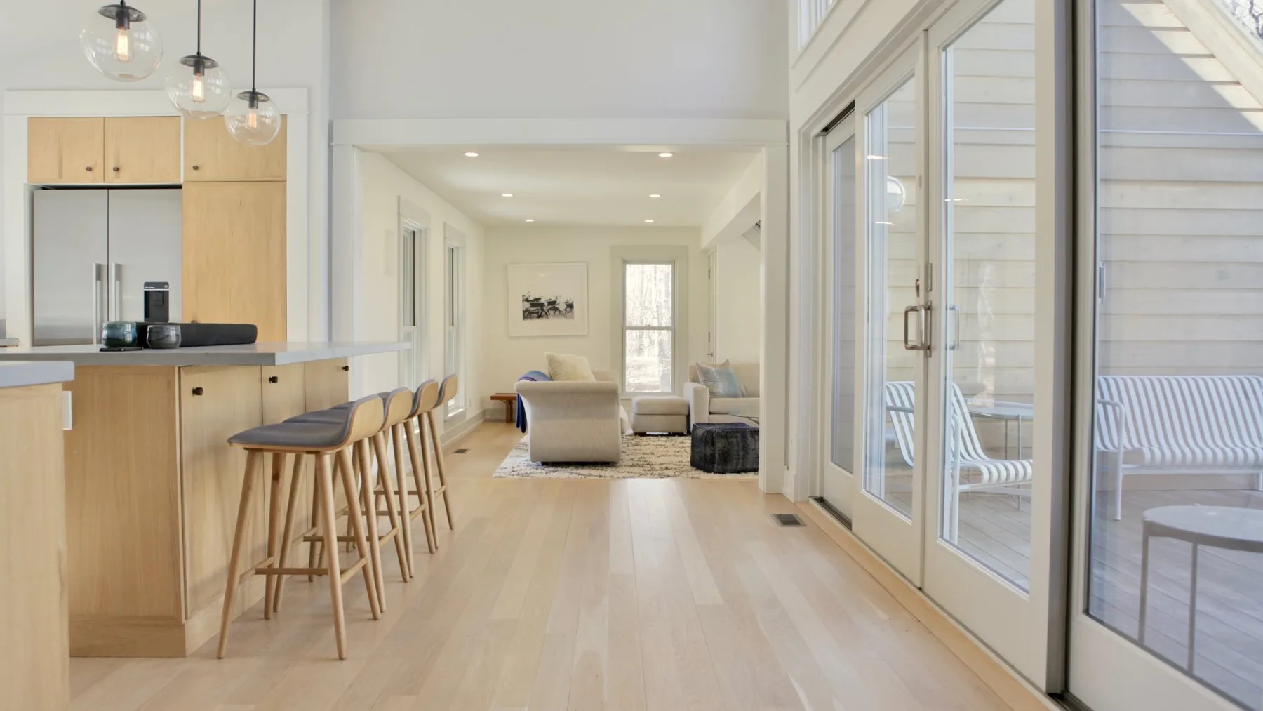 An open-plan kitchen and living area with a long counter and large windows.