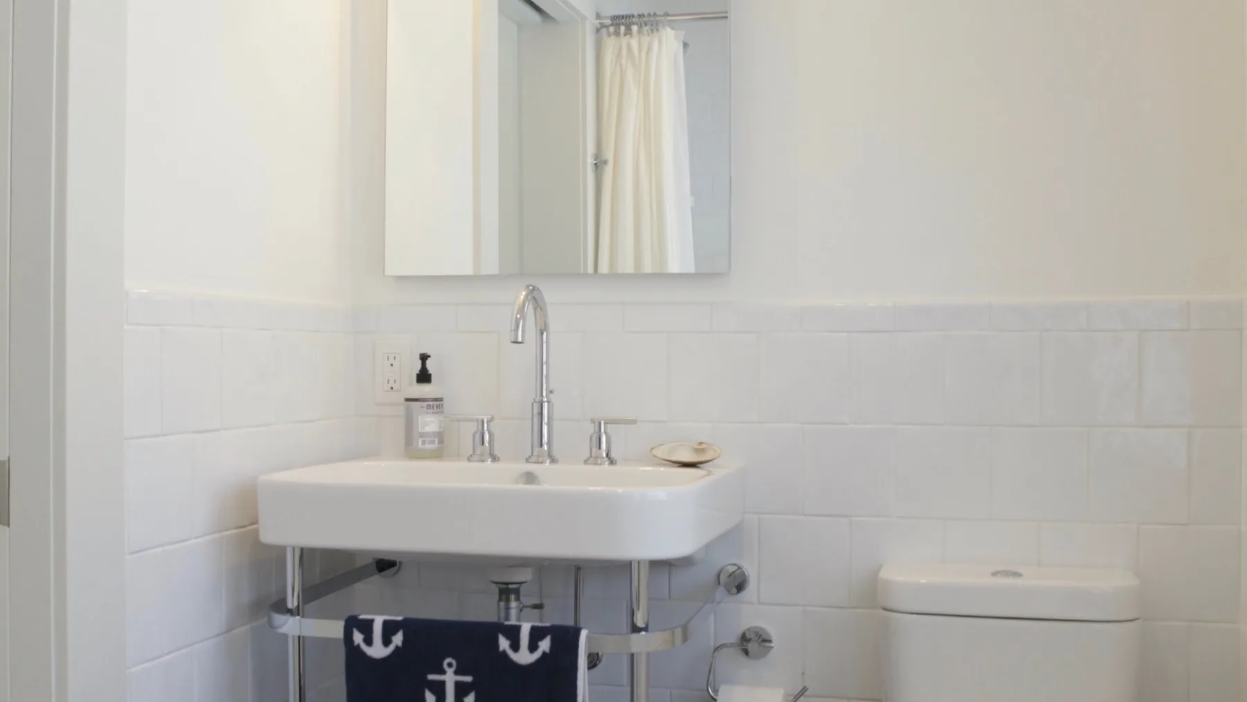 A bright bathroom with a wall-mounted sink and toilet.