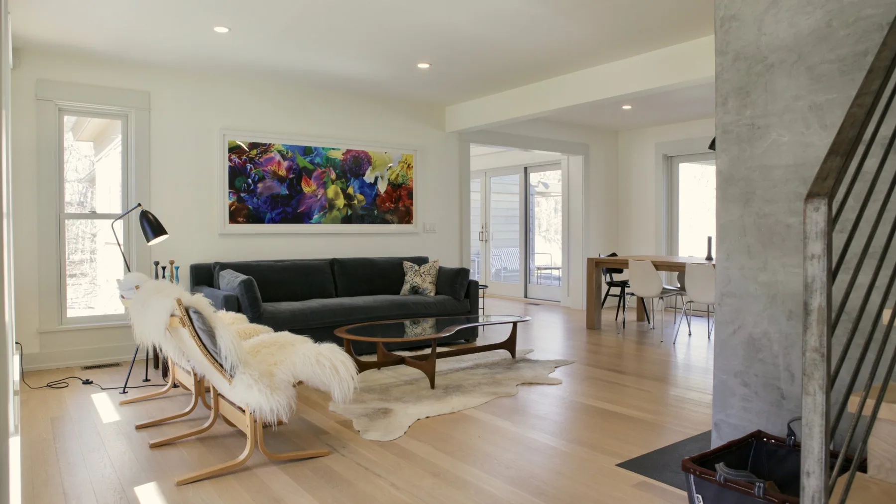 Una sala de estar luminosa con asientos, una mesa baja y arte colorido en la pared.