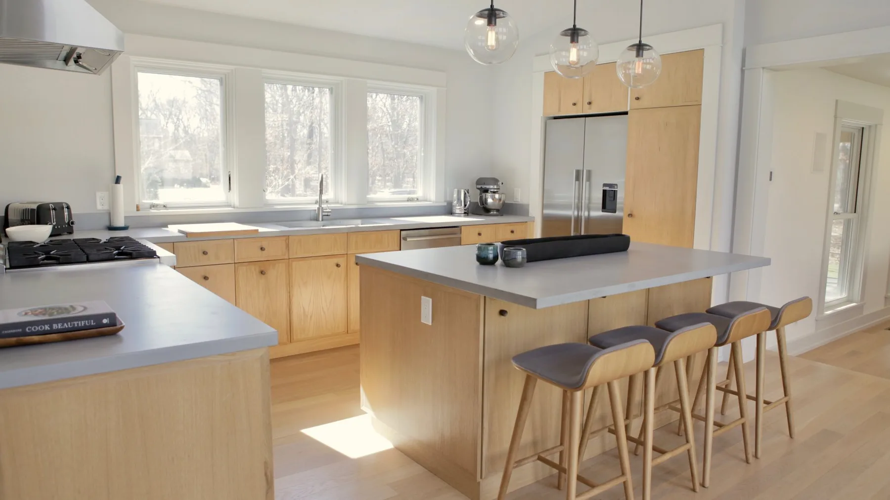 A bright kitchen with a central island and wooden stools.