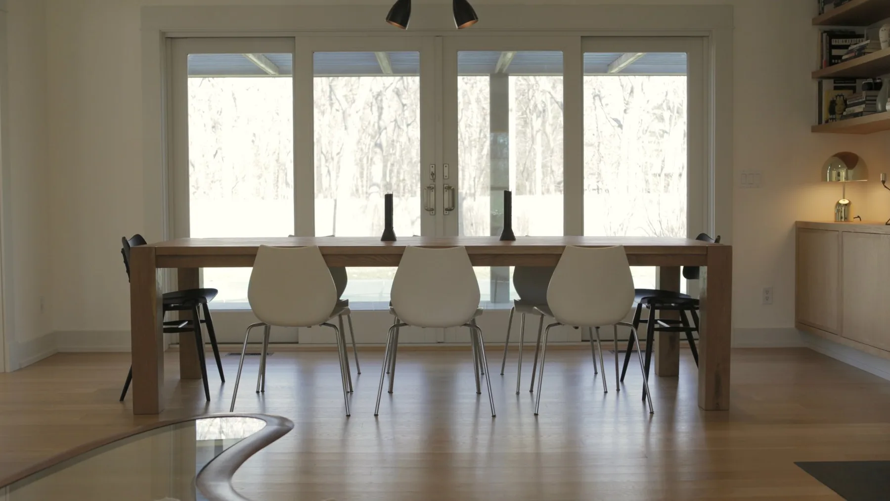 Un comedor con una mesa larga y sillas frente a grandes ventanales.