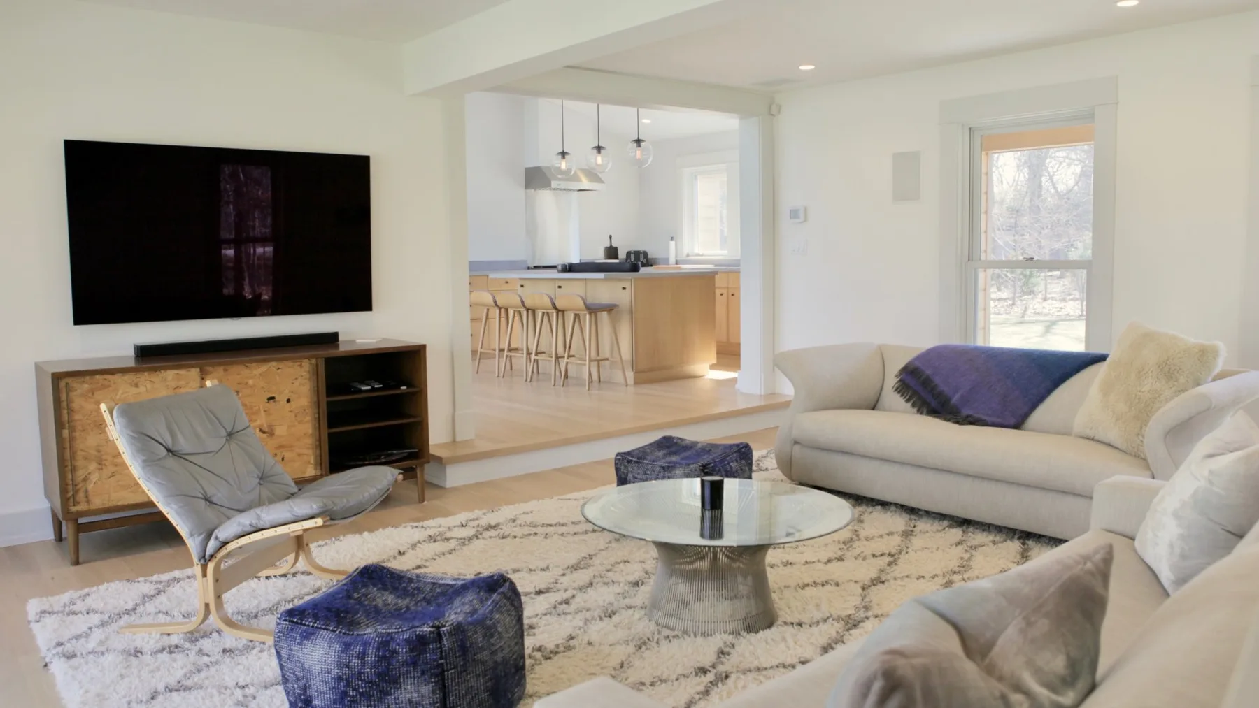 A bright living room with seating around a glass coffee table and a television.