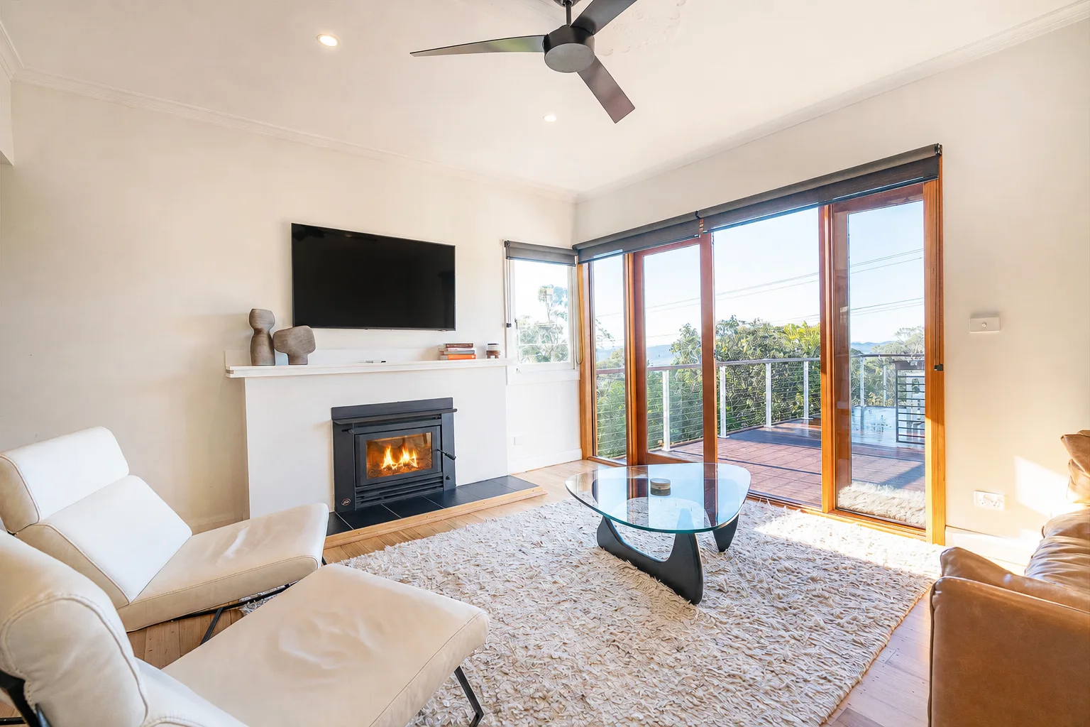 Una sala de estar con chimenea y grandes puertas de vidrio que dan a una terraza.