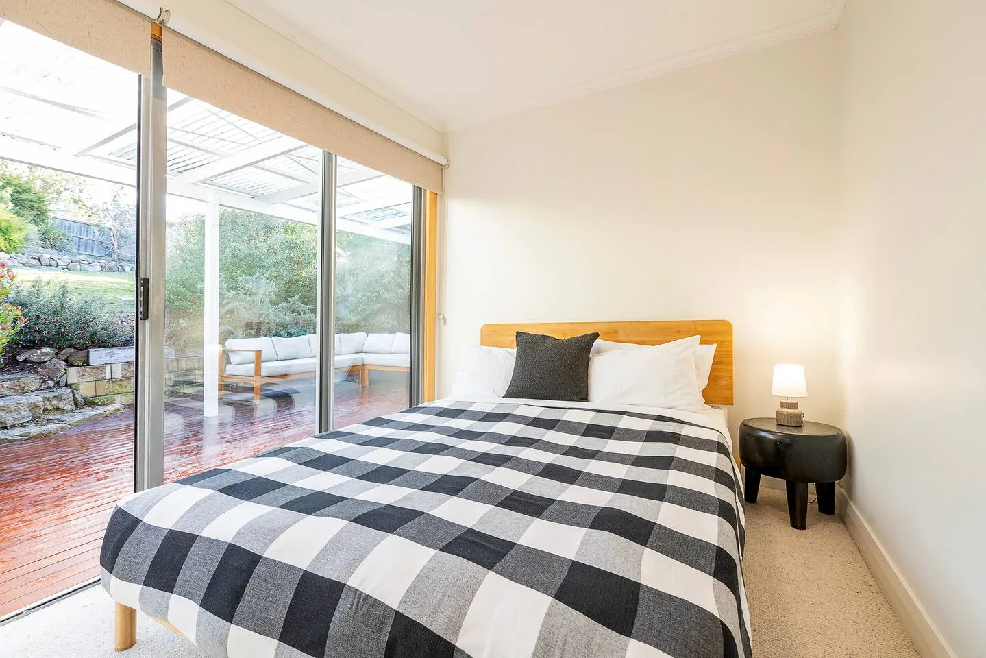Un dormitorio con una cama junto a una gran puerta corrediza de vidrio que da a una terraza.