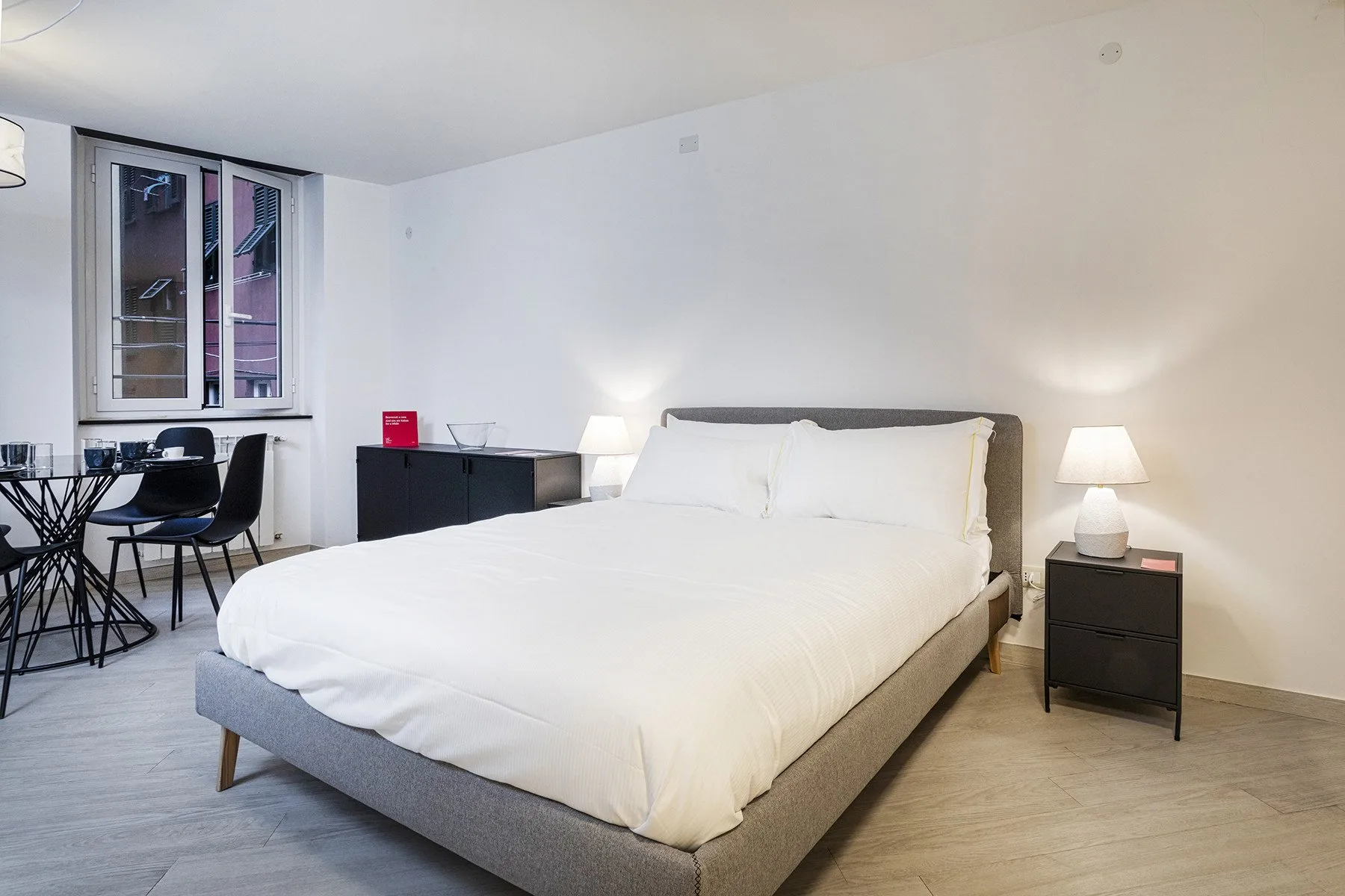 Un dormitorio con una cama grande y una pequeña zona de comedor junto a la ventana.