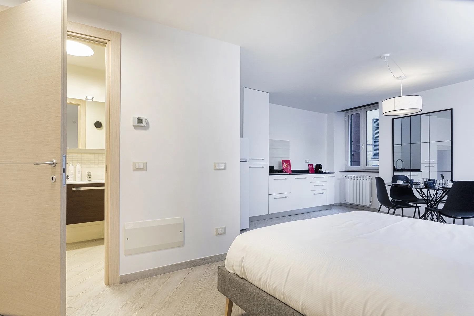 Un dormitorio luminoso con una cama grande, armarios blancos y una mesa de comedor.