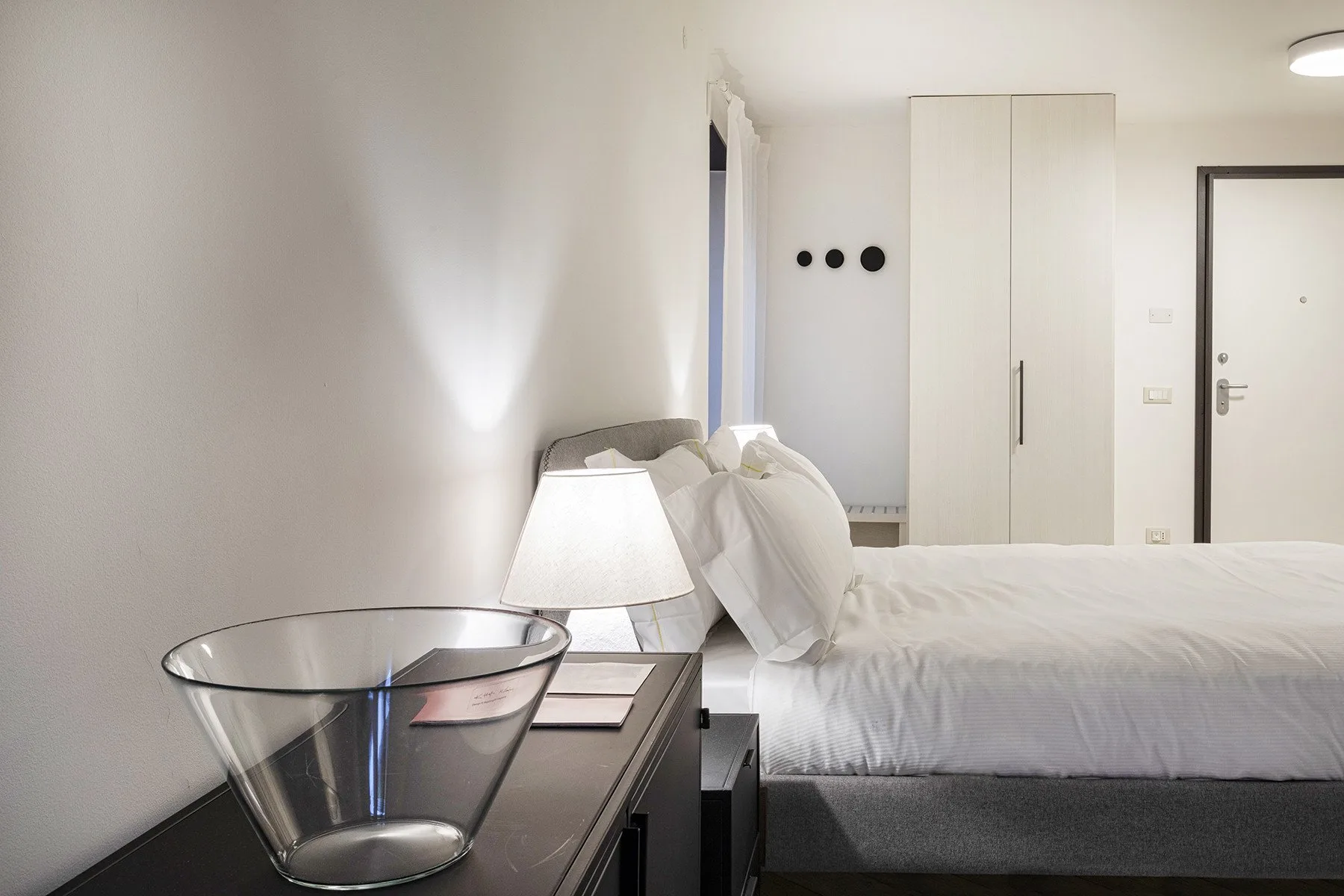Un dormitorio luminoso con una cama bien tendida y una mesita de noche.