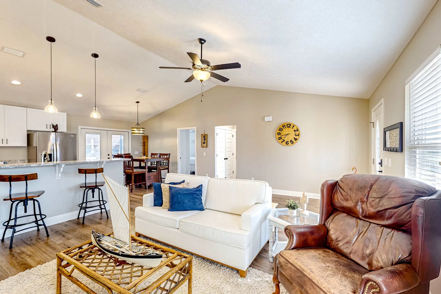 An open-plan living room with a white sofa and a kitchen bar.
