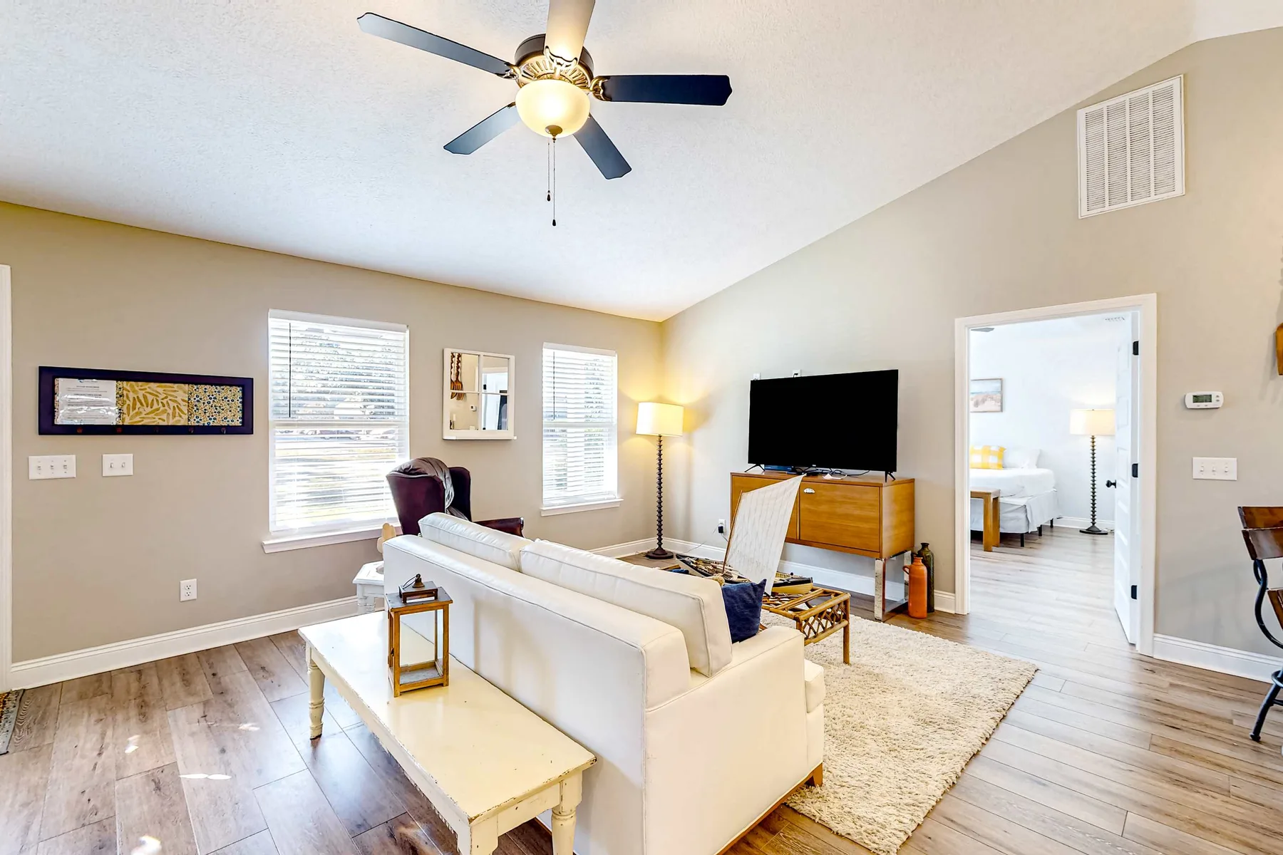 A bright living room with seating, a television, and a rug.
