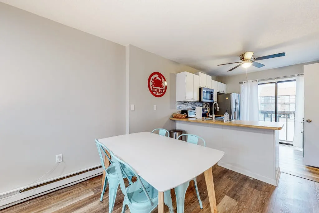 An open dining and kitchen area with a table beside a breakfast counter.