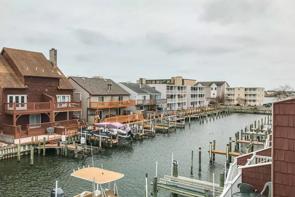 Waterfront buildings and docks line a canal with boats moored along the shore.