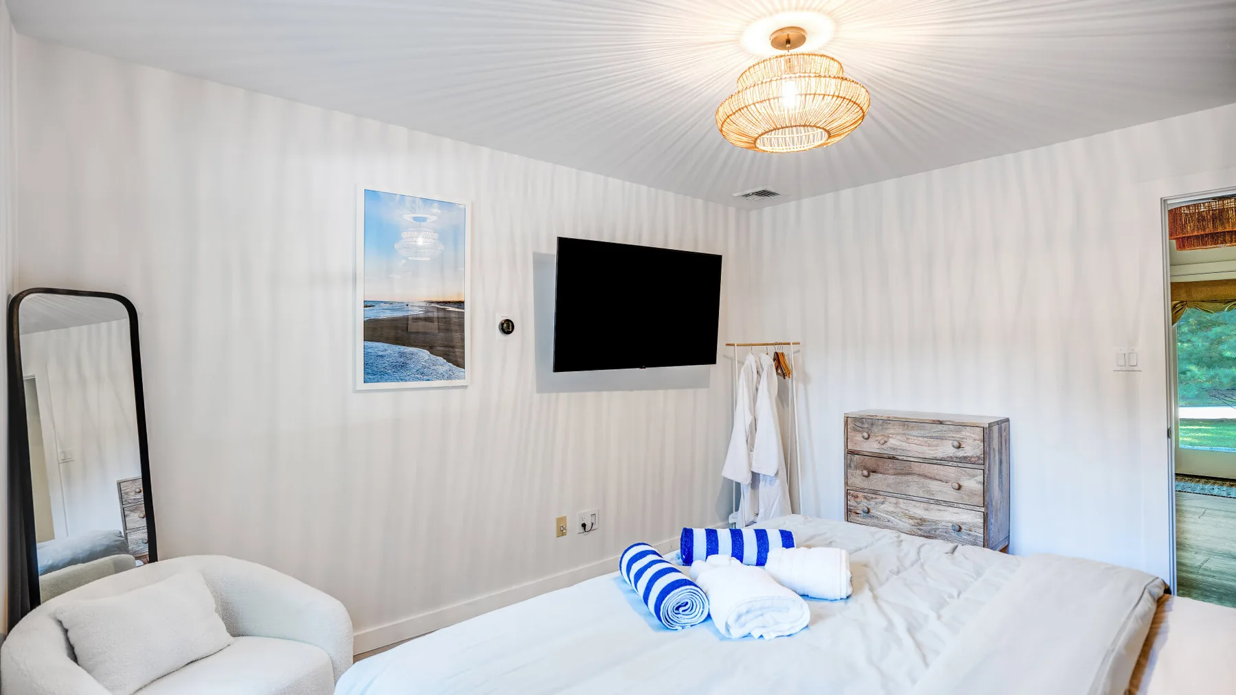Un dormitorio con cama, televisor en la pared y una lámpara de techo encendida.