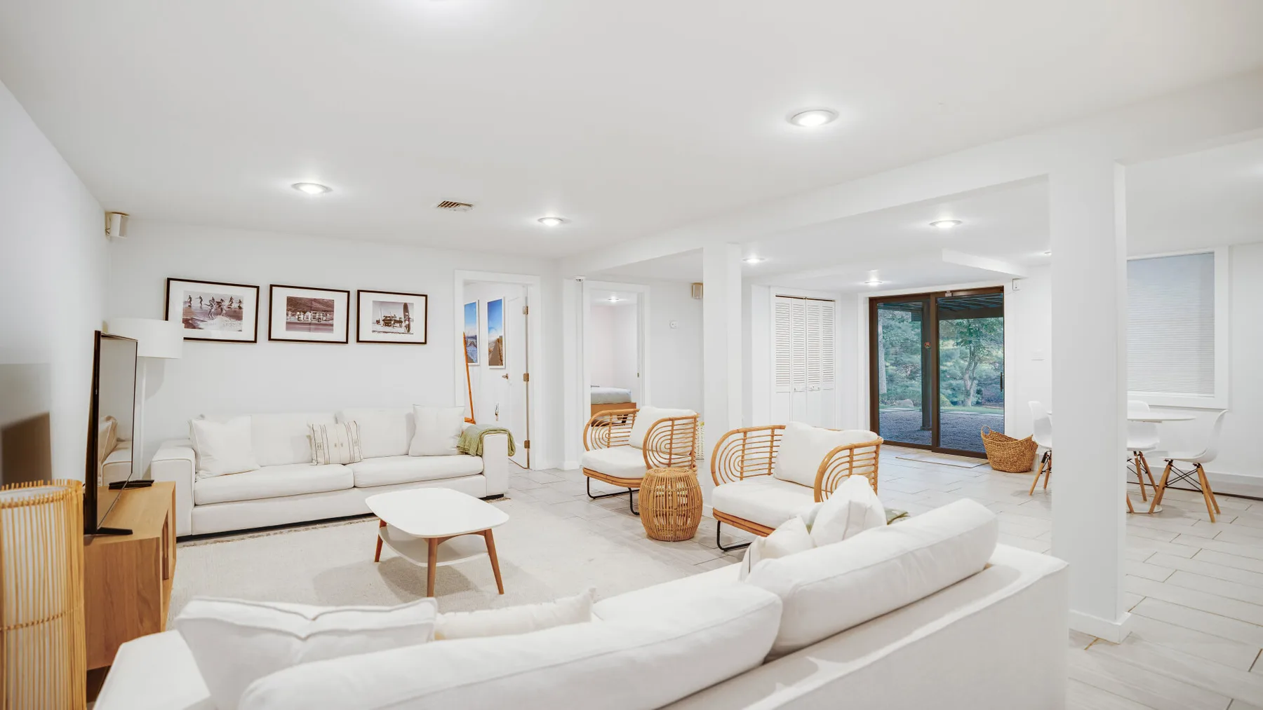 Una sala luminosa con asientos blancos y un comedor junto a grandes puertas de vidrio.