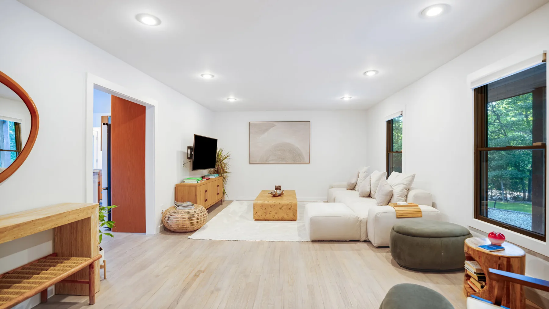 Una sala de estar luminosa con asientos, una mesa de centro y grandes ventanas.