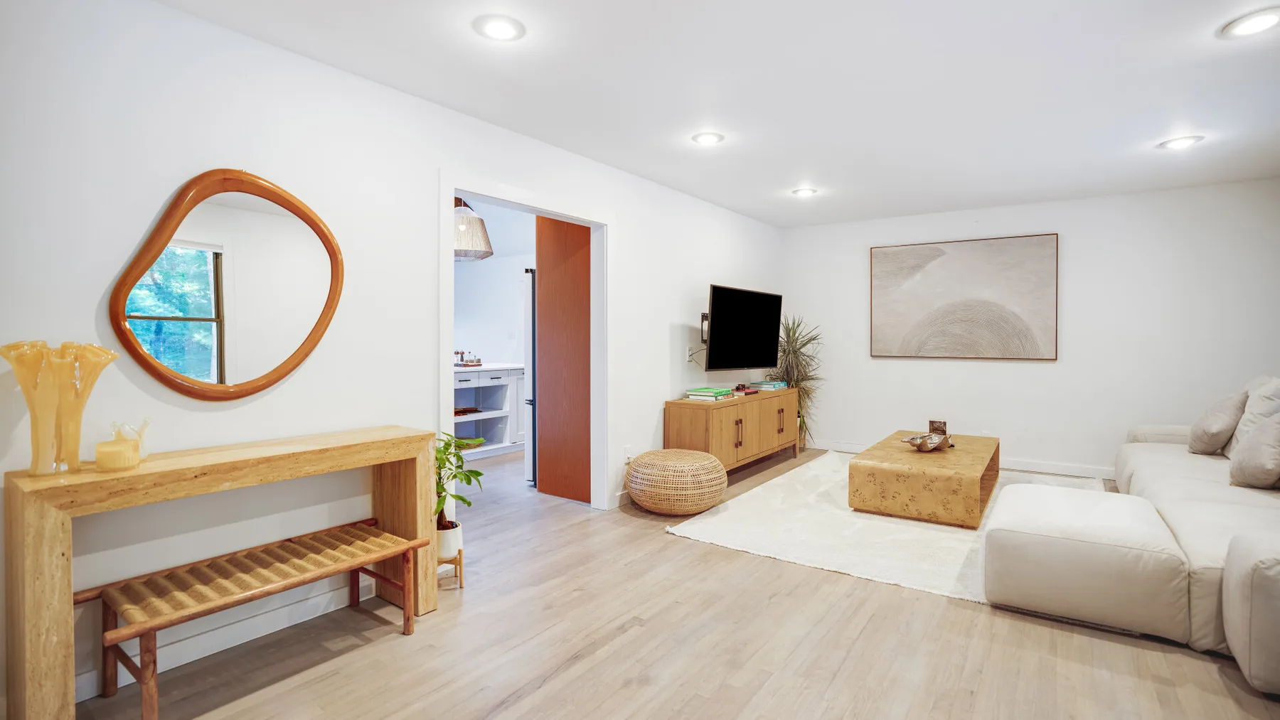 Una sala luminosa con asientos claros, una mesa de centro de madera y arte en la pared.