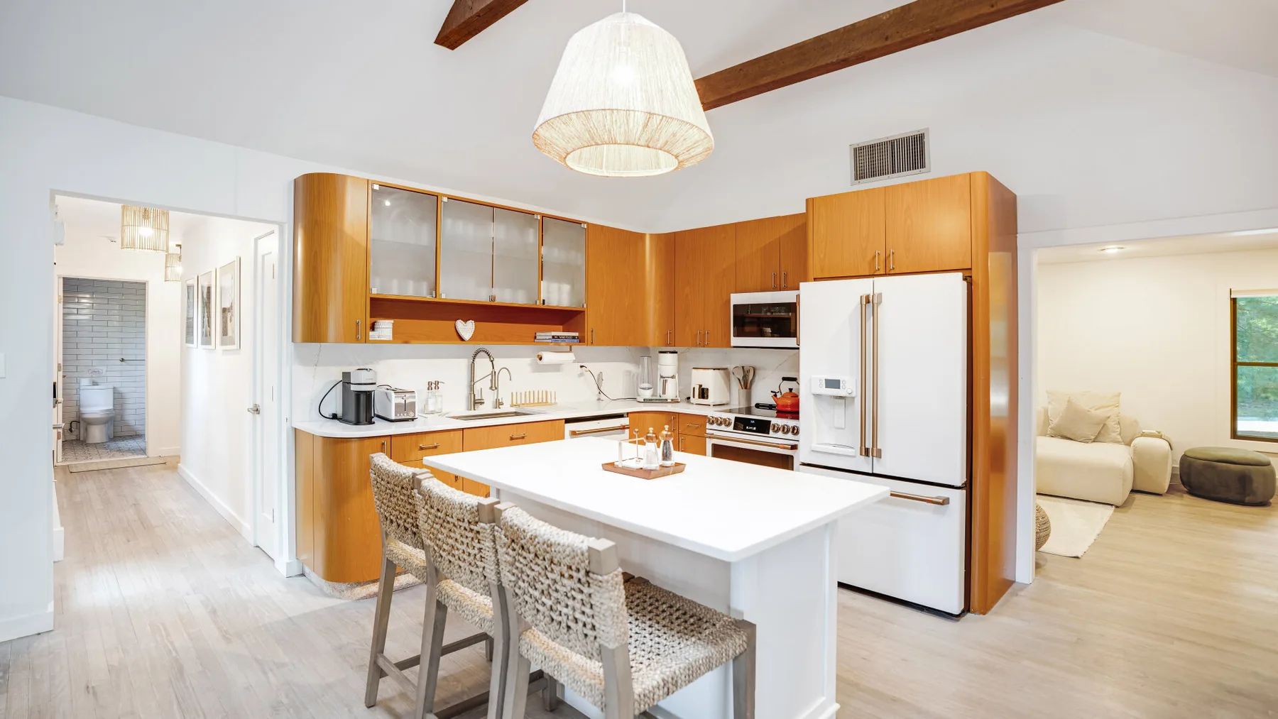 Una cocina luminosa con gabinetes de madera, una isla central y asientos tejidos.