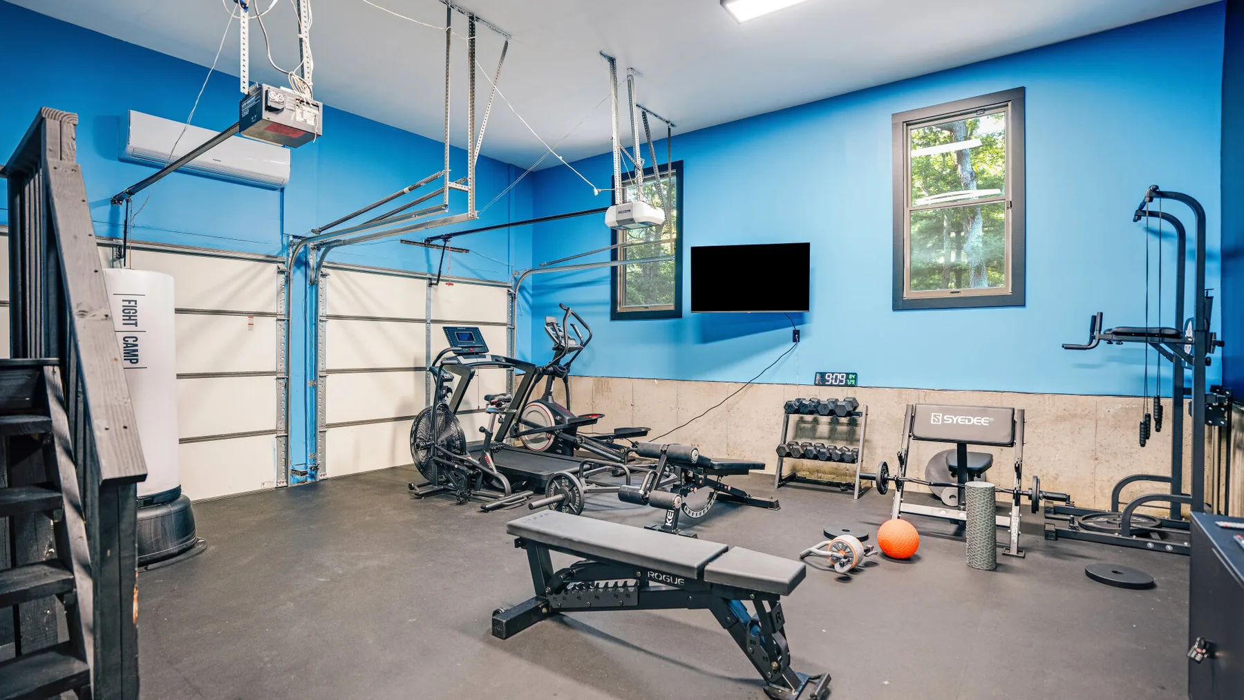 Un gimnasio con máquinas de ejercicio, pesas y un banco de entrenamiento.