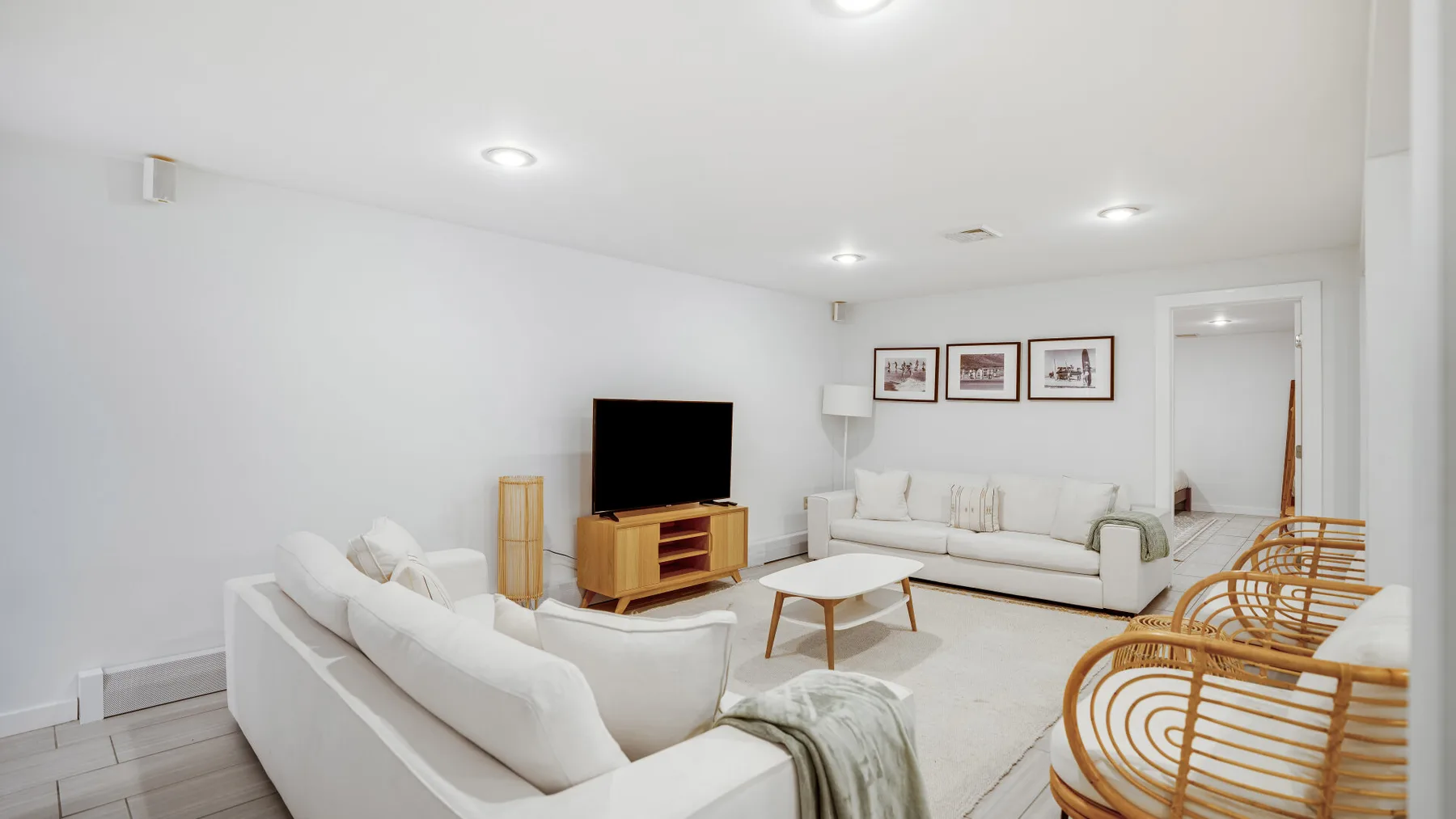 Una sala luminosa con asientos blancos, un televisor y una mesa de centro baja.