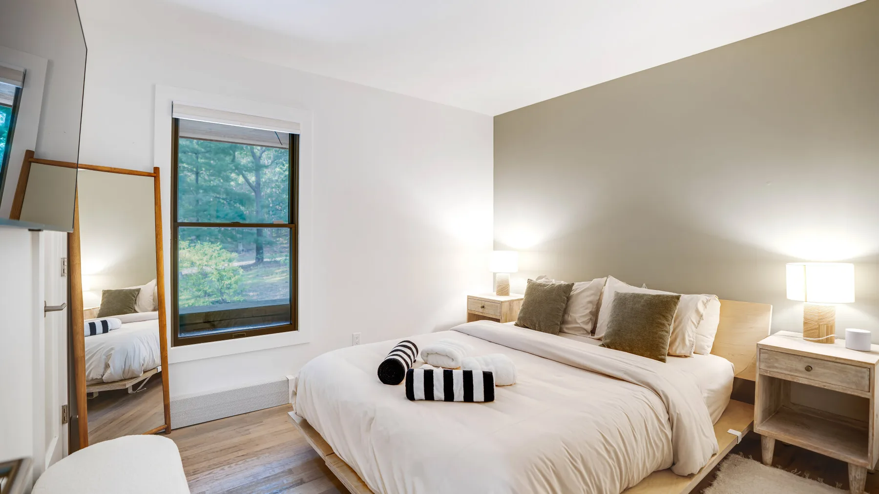 Un dormitorio con una cama bien tendida y una ventana con vistas a los árboles.