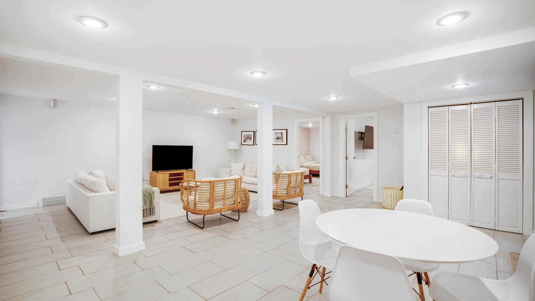 Un salón-comedor diáfano y luminoso con asientos blancos y una mesa redonda.