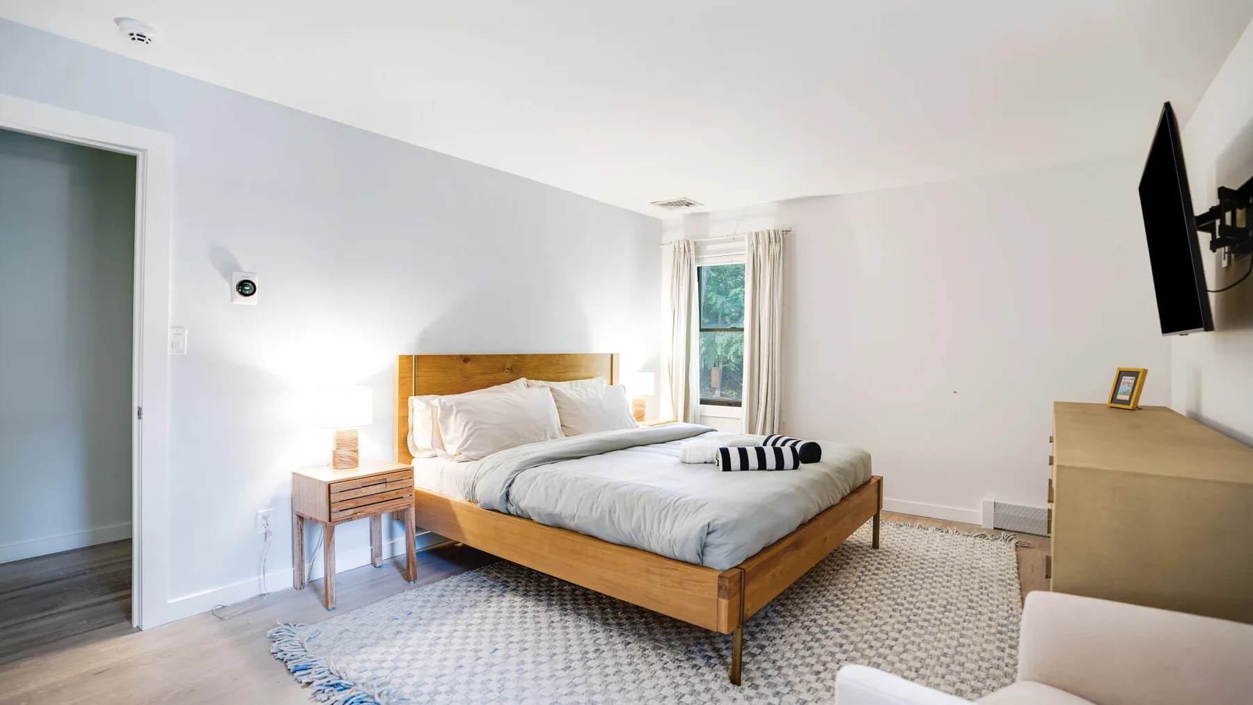 Un dormitorio con una cama de madera, mesitas de noche y una ventana.
