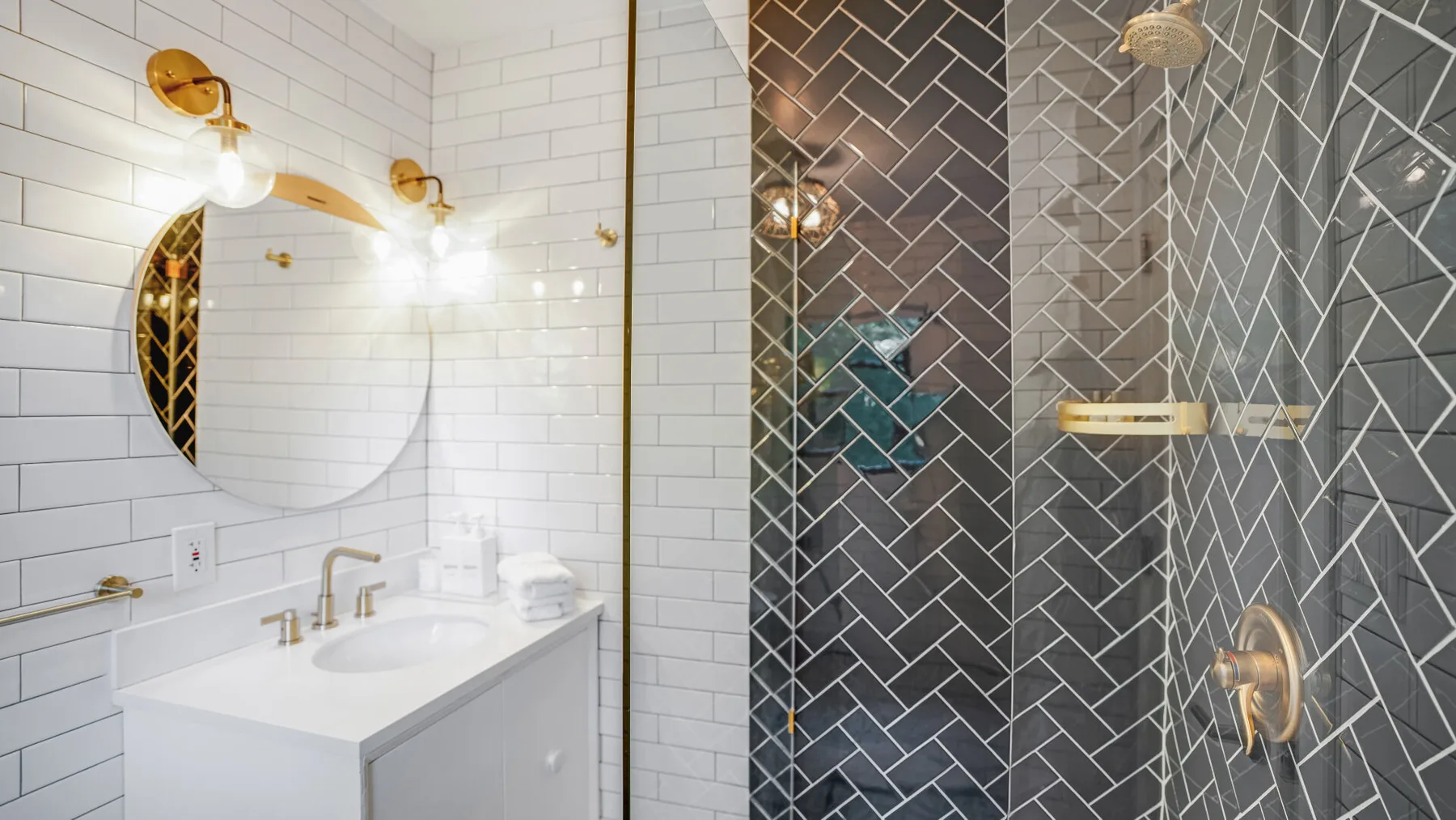 Un lavabo de baño con espejo redondo junto a una ducha revestida de azulejos.