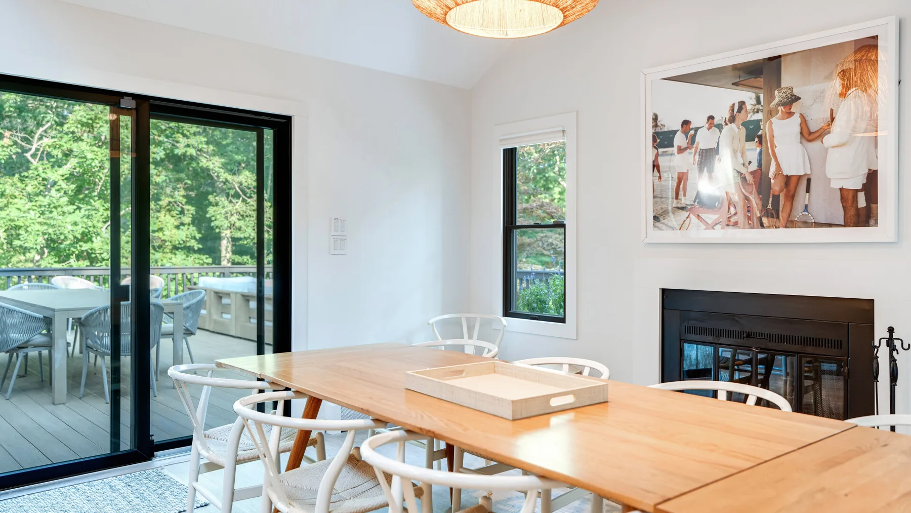 Comedor con una mesa de madera junto a grandes puertas de vidrio y vistas a la vegetación.