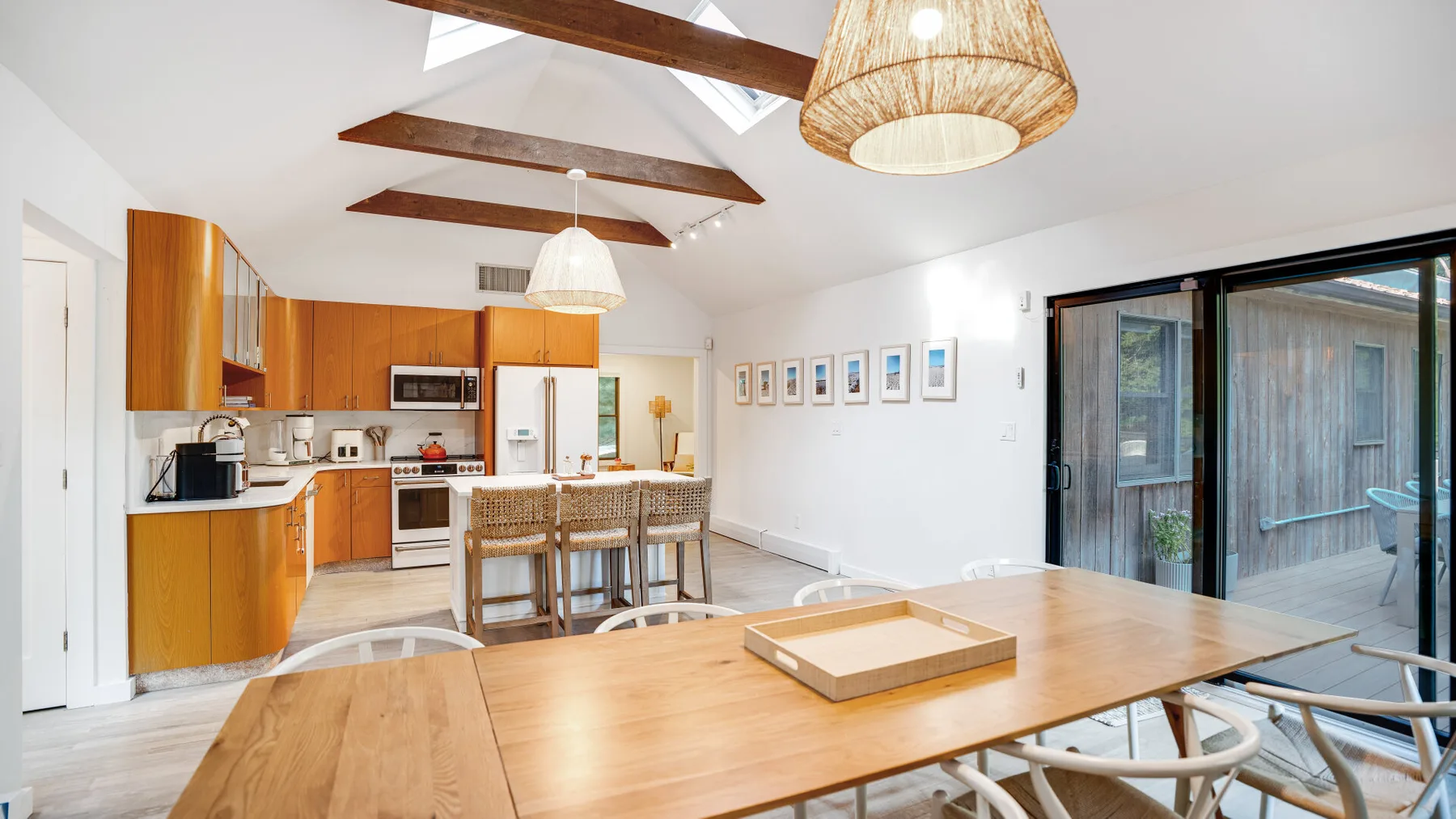 Una luminosa cocina-comedor de planta abierta con mesas de madera y vigas expuestas.