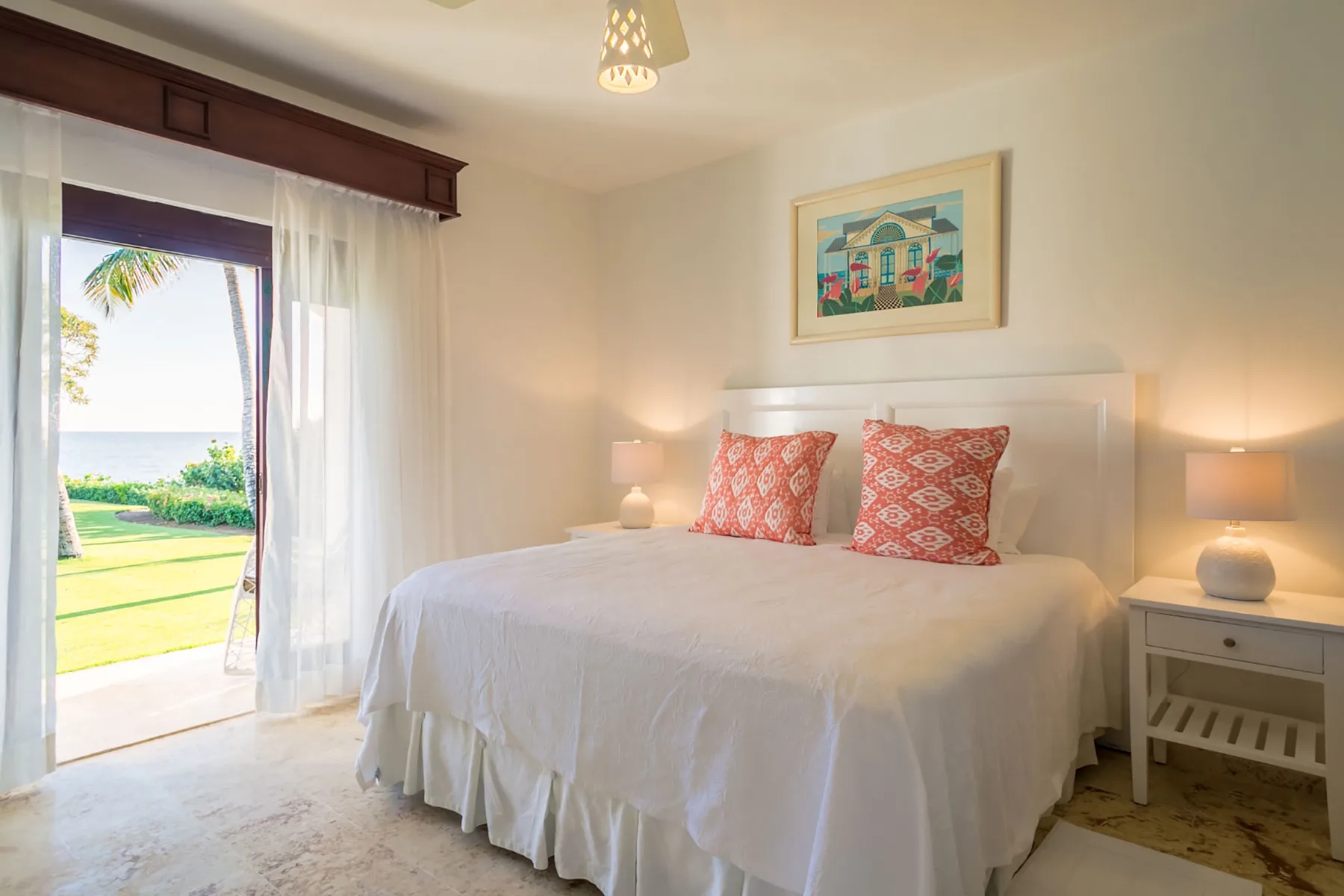 A bright bedroom with a neatly made bed and a glass door opening to a garden.