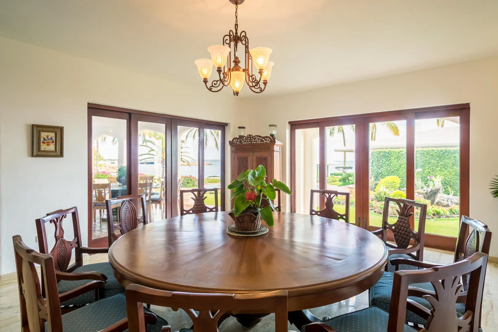 A dining room with a large wooden table and windows overlooking a garden.