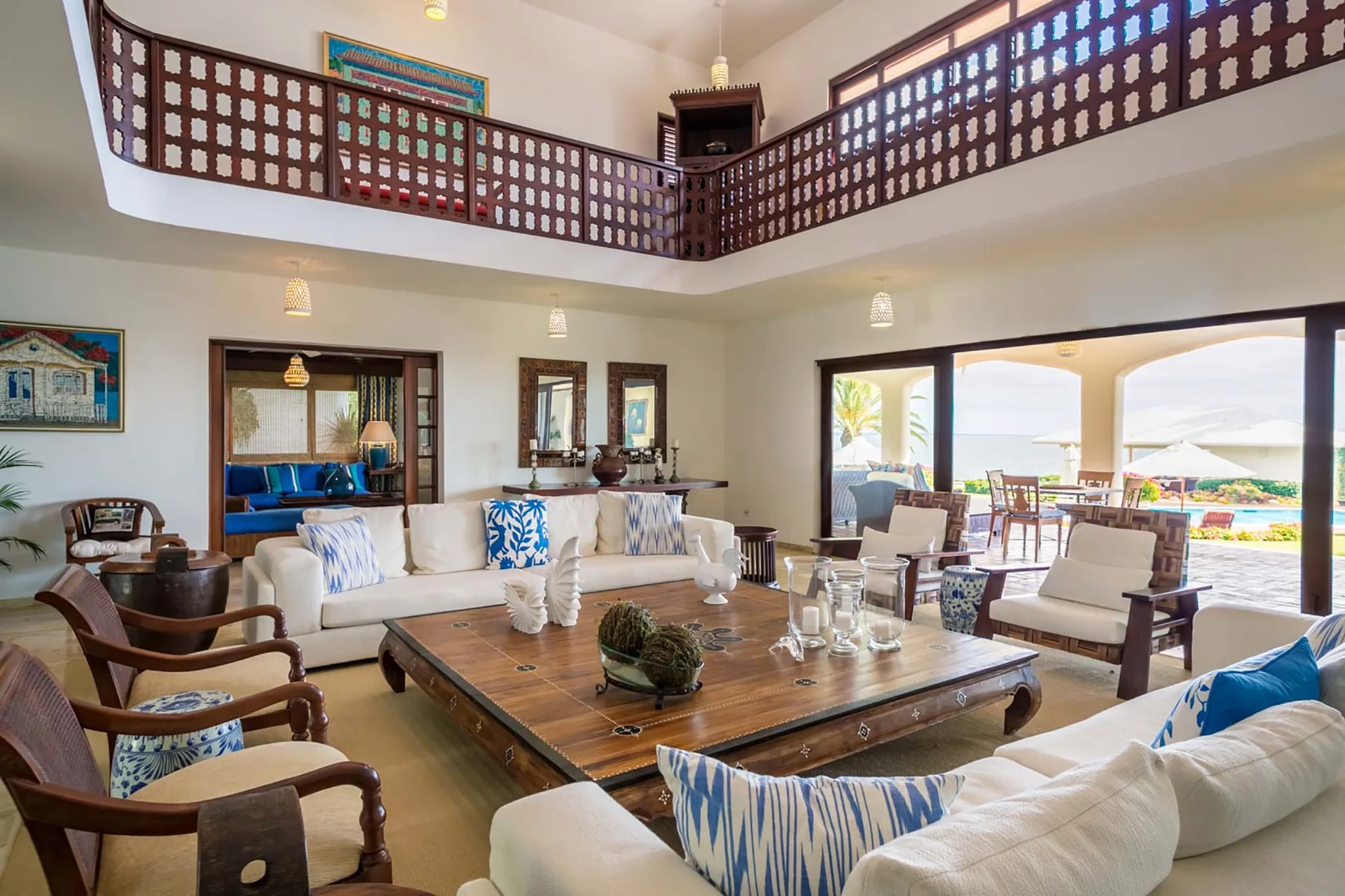 A spacious living room with seating around a low wooden table and open doors to a patio.