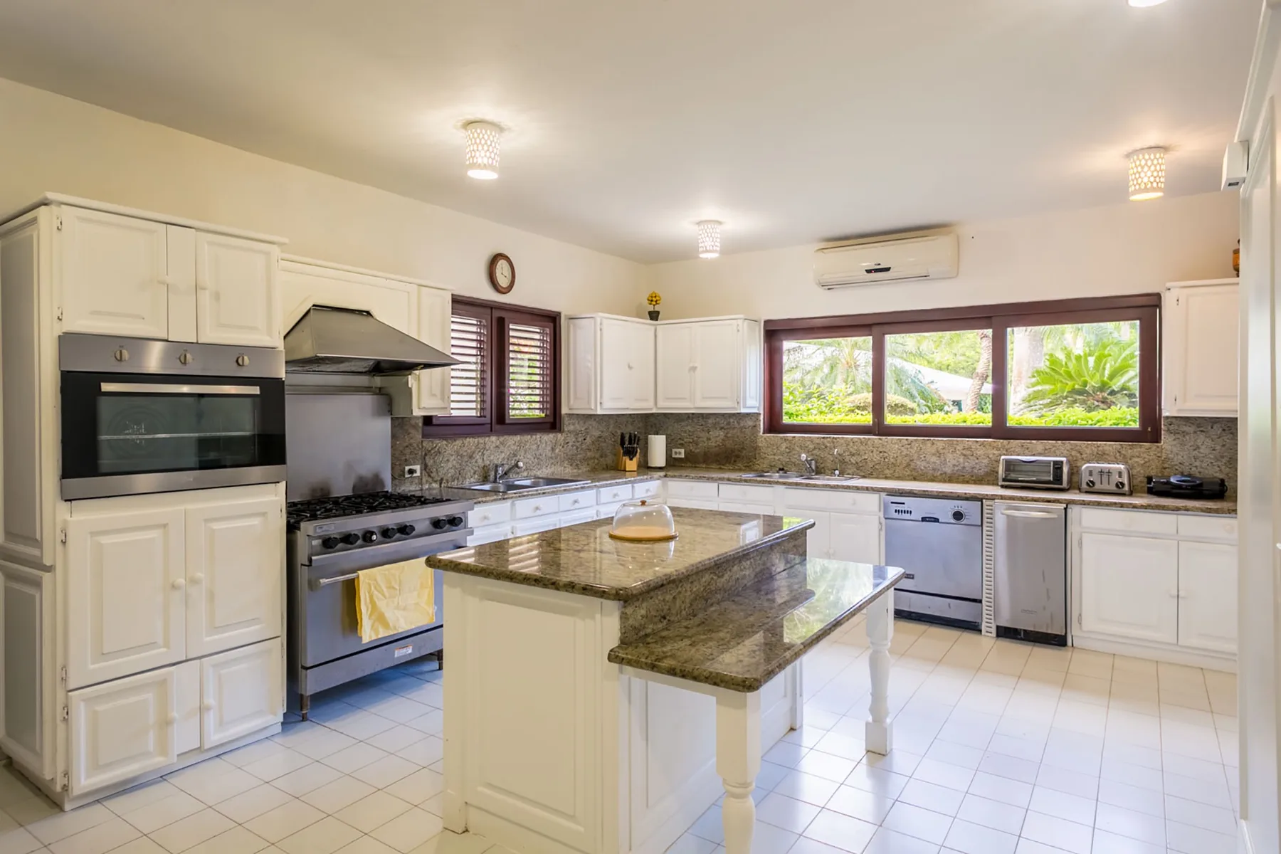 A bright kitchen with white cabinets, stainless steel appliances, and a central island.