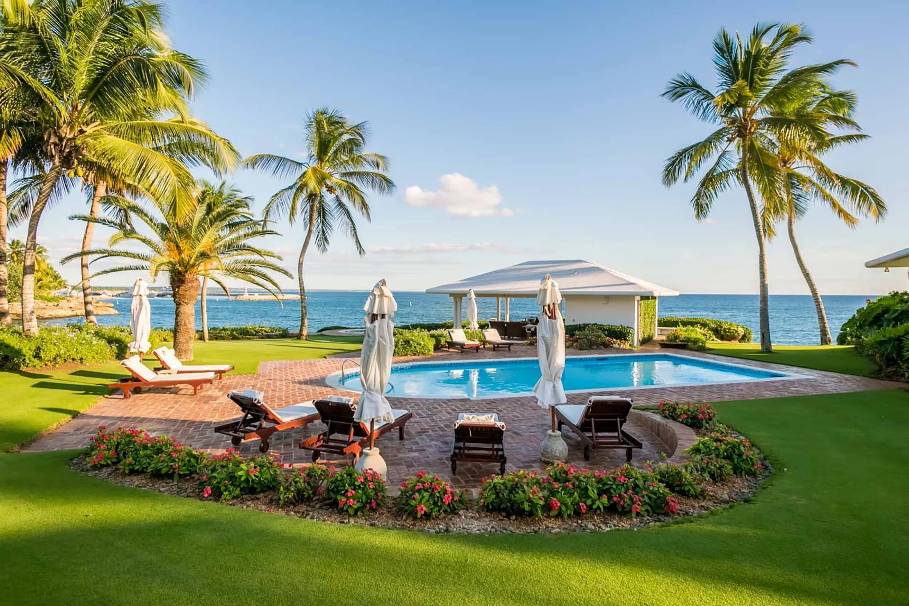 A landscaped pool area with lounge seating overlooks the ocean.