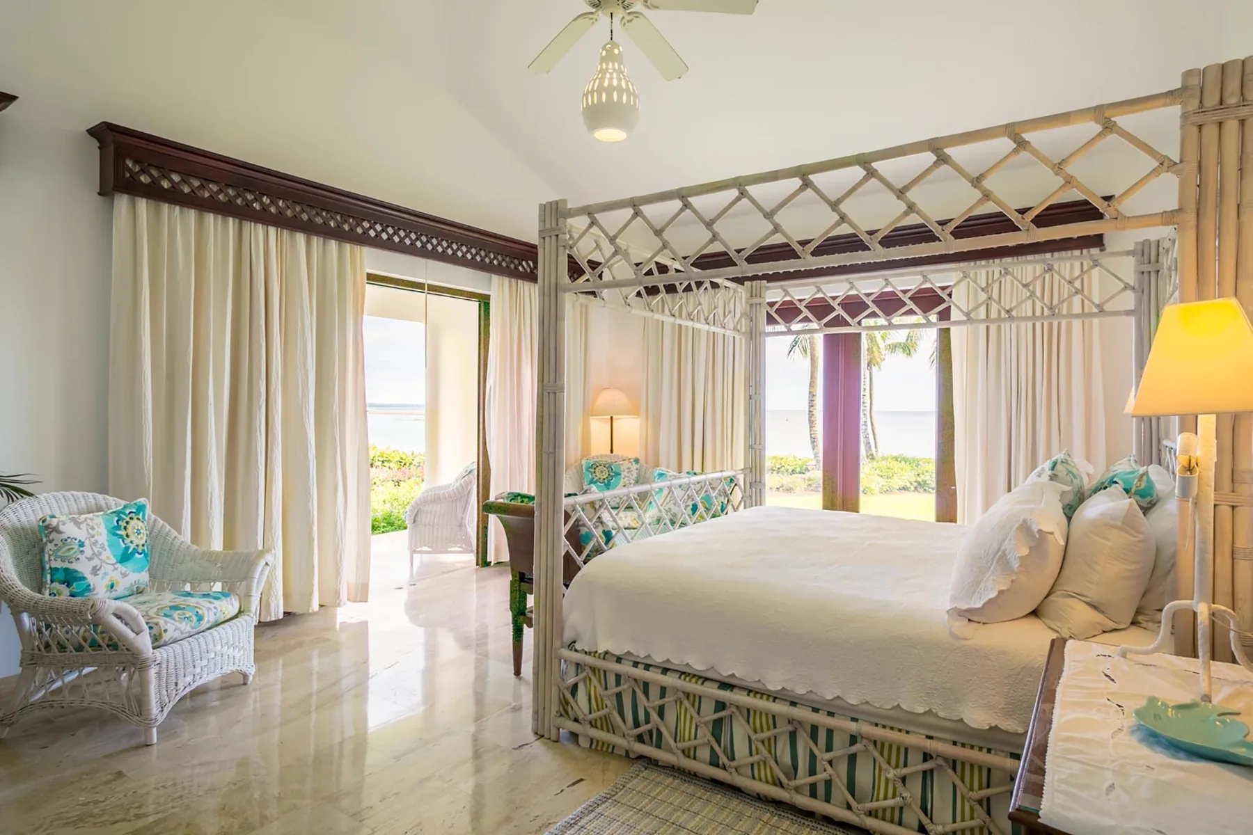 A bright bedroom with a canopy bed and glass doors opening onto greenery.
