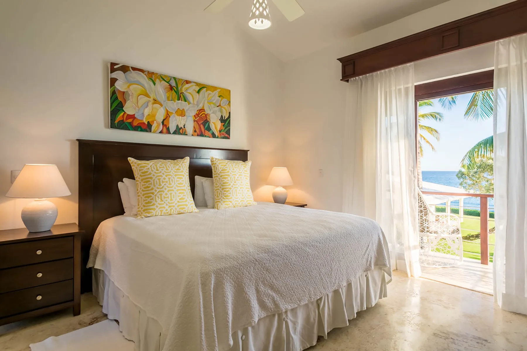 A bedroom with a neatly made bed and colorful floral artwork above the headboard.