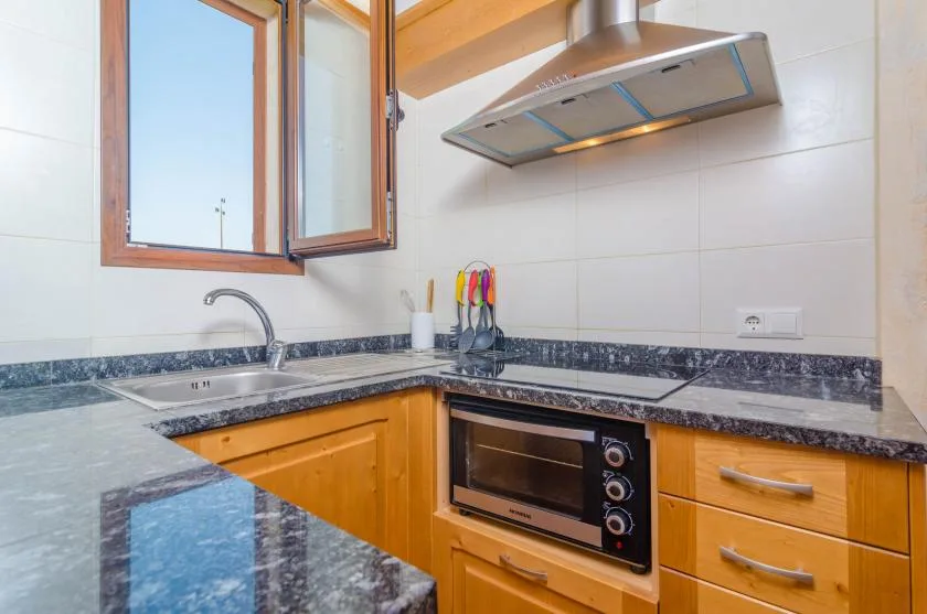 Una cocina con armarios de madera, una encimera y un horno empotrado.