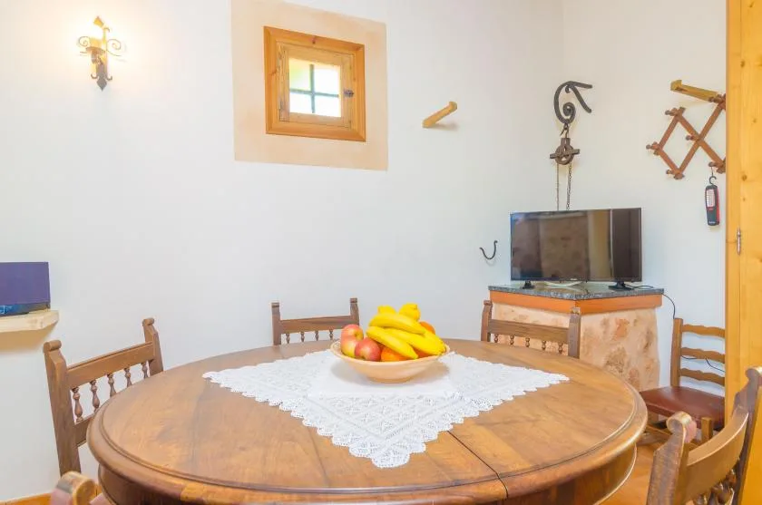 Un comedor con una mesa redonda de madera y un centro de frutas.