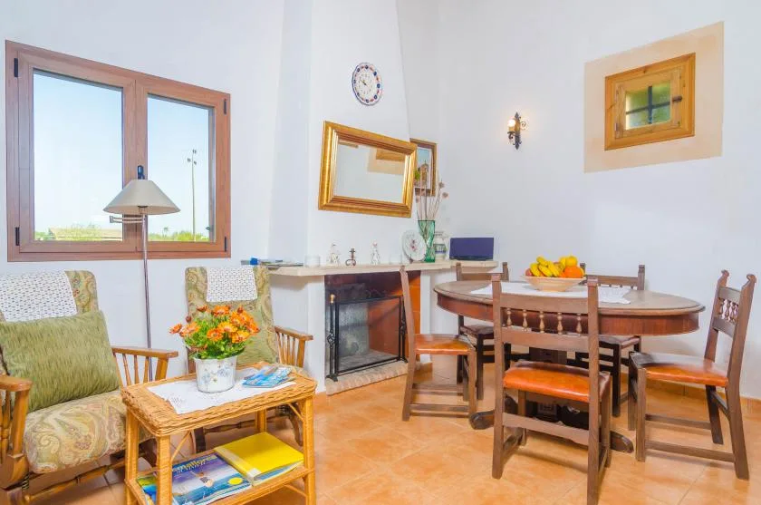 Zona de comedor y estar con una mesa de madera y una chimenea.