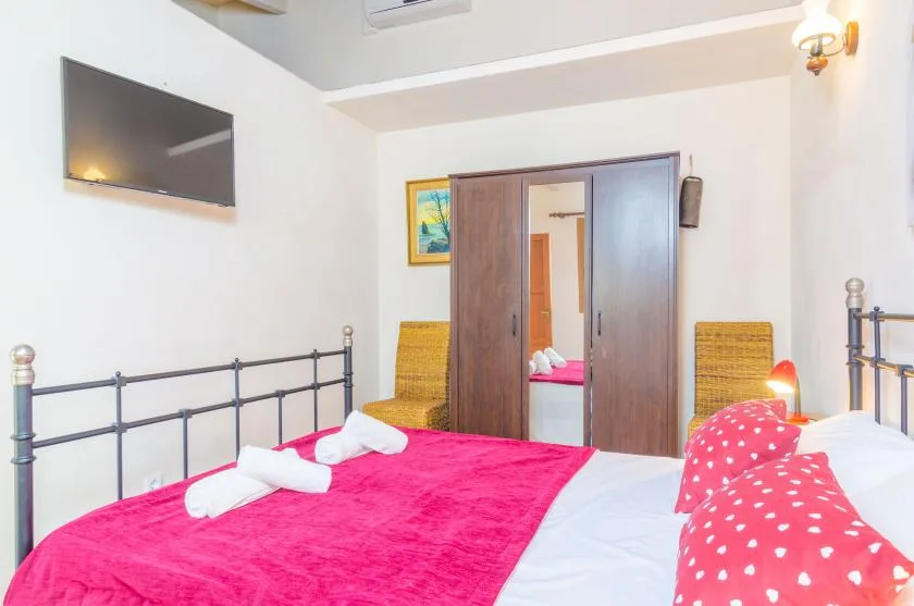 Un dormitorio con dos camas, un armario y un televisor montado en la pared.