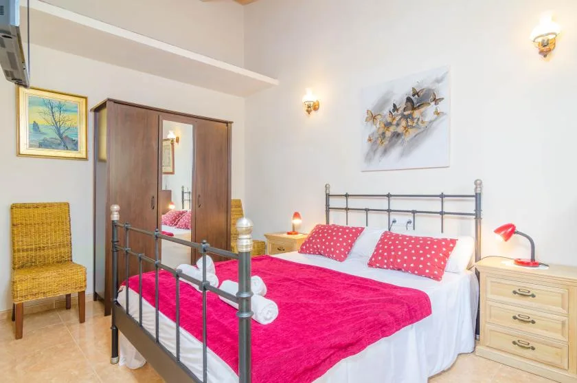 Un dormitorio con una cama de estructura metálica y ropa de cama rosa intenso.