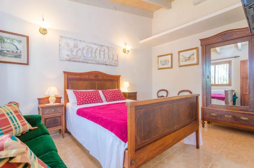 Un dormitorio con una cama de madera, ropa de cama rosa intenso y una zona de estar verde.